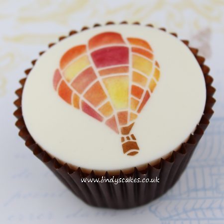 Hot air balloon stencilled onto sugarpaste using Lindy's air transport cupcake stencil set and coloured food dusts