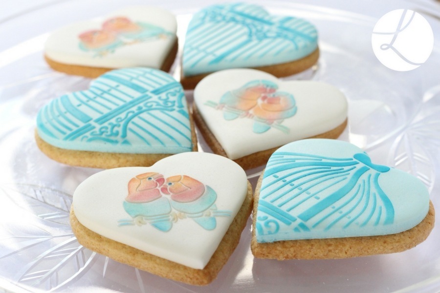Lindy's lovebird stencil used on heart shaped cookies in pastel peach and aqua